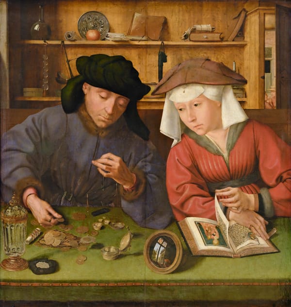 A man in a dark robe weighs gold coins on a small balance while his wife, seated beside him, turns away from an illuminated devotional book to watch.